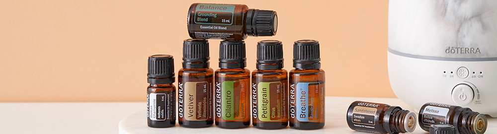 An essential oil diffuser releasing soft mist on a wooden desk beside books and a notebook